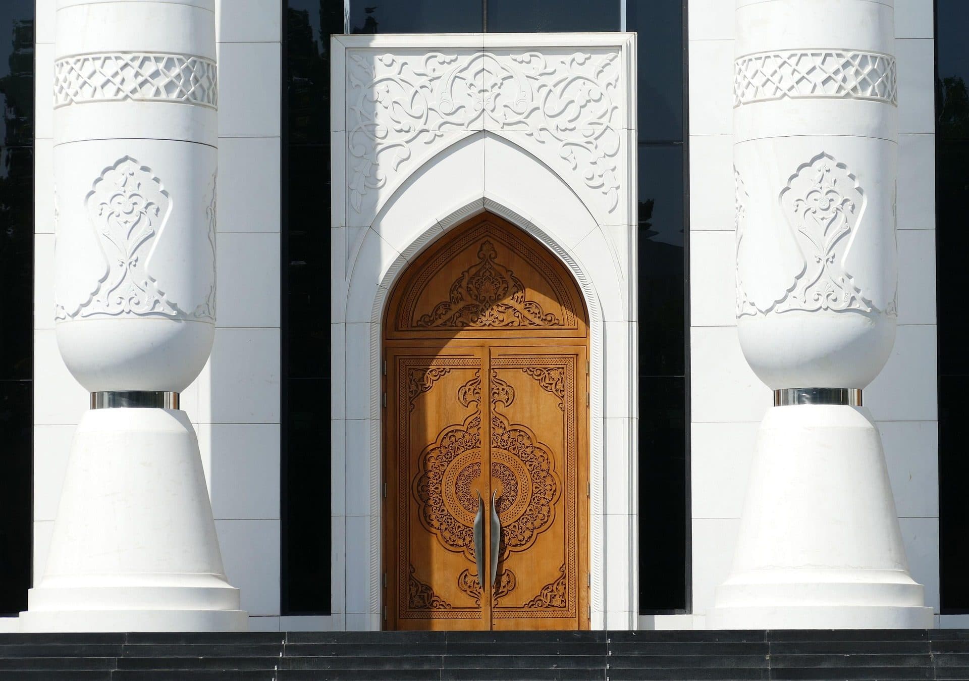 A carved wooden door between white columns.