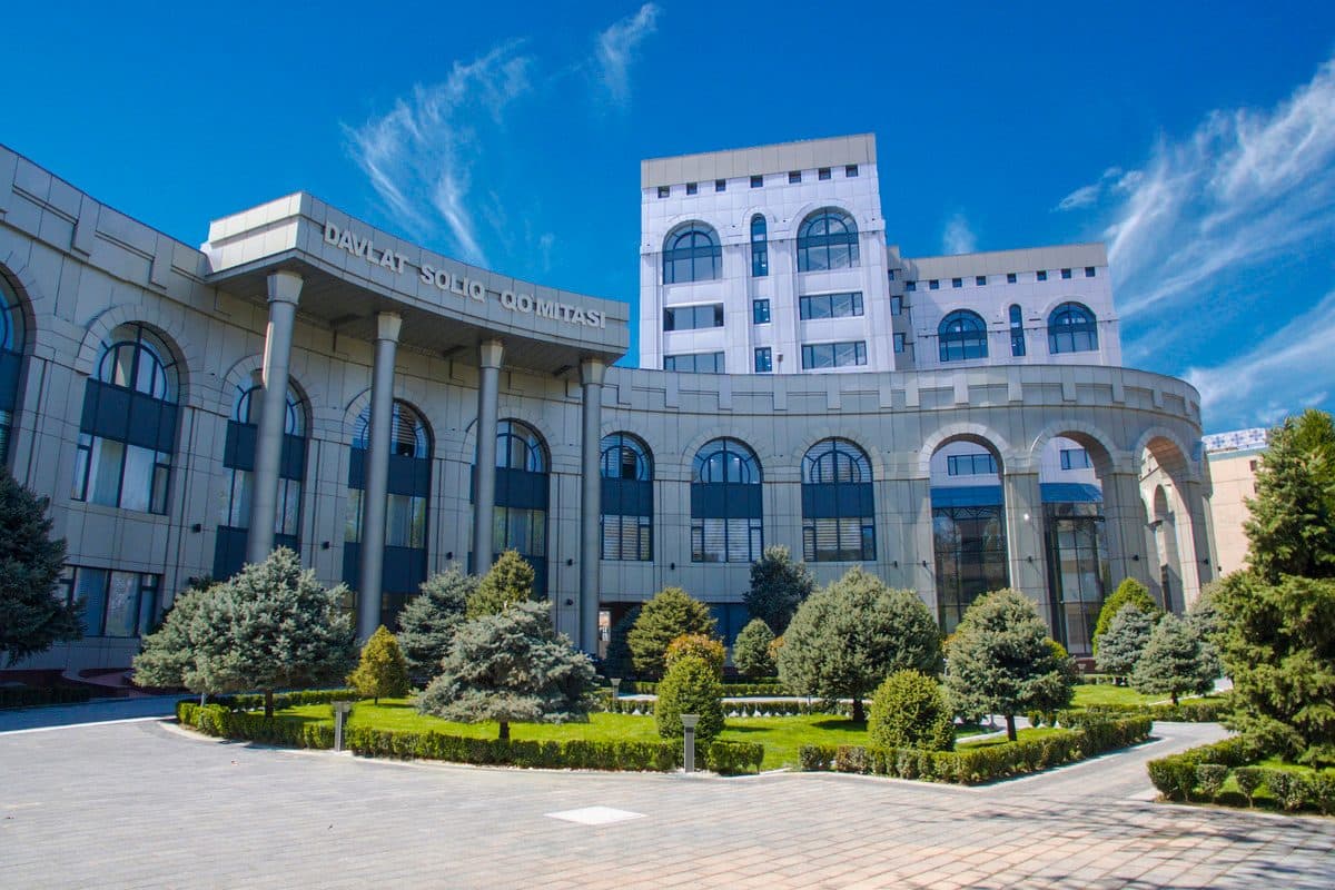 A columned government building behind clipped hedges.